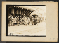 [recto] Evacuees of Japanese ancestry waiting for the train which will take them to an assembly center from where they later will be transferred to a War Relocation Authority center to spend the duration. ;  Photographer: Albers, Clem ;  San Pedro, California